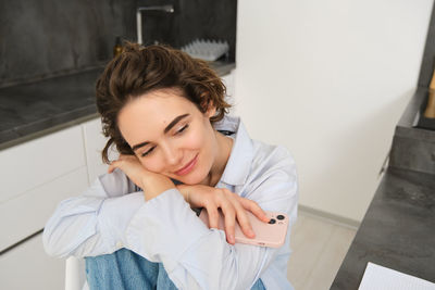 Portrait of young woman standing against wall