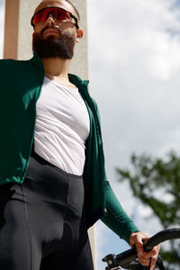 Side view of young man standing against sky