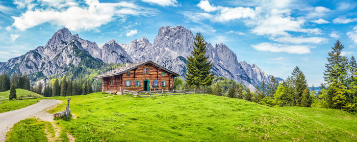 Scenic view of trees and house against mountain and sky