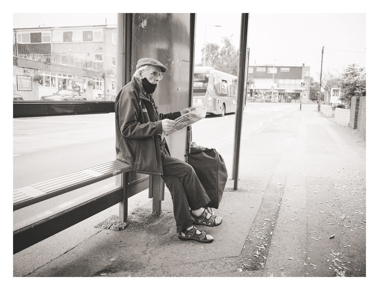 FULL LENGTH OF MAN SITTING ON BENCH AT STREET