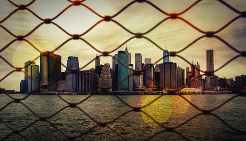 View of cityscape seen through chainlink fence