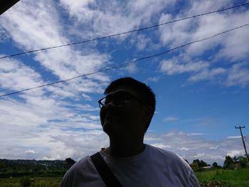 Low angle portrait of man standing against sky