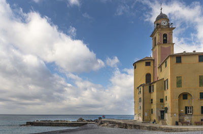 Clock tower by sea against sky