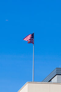 Low angle view of flag against clear blue sky