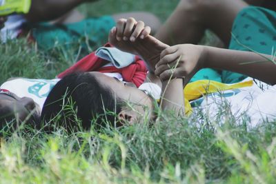 Carefree friends lying on grassy field at park