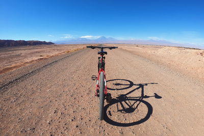 Bicycle parked on road against blue sky