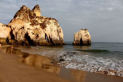 Rock formation on beach against sky