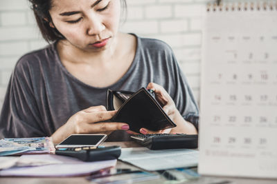 Young woman using mobile phone while sitting on table