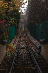 Railroad tracks along plants and trees with a funicular in a distance on a rainy autumn day