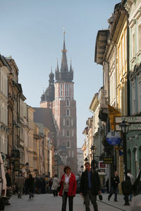 People walking in city against clear sky