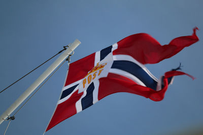 Low angle view of flag on pole against blue sky