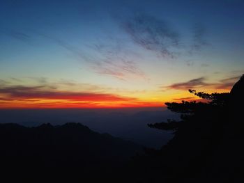 Scenic view of silhouette mountains against orange sky