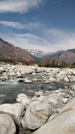 Scenic view of river against sky with snow covered mountain