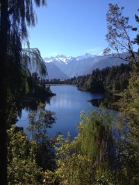 Scenic view of lake and mountains against clear blue sky