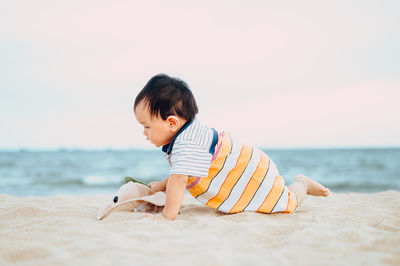 Cute boy playing on beach against sea