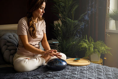 Young woman sitting on bed at home