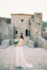 Rear view of woman standing against wall