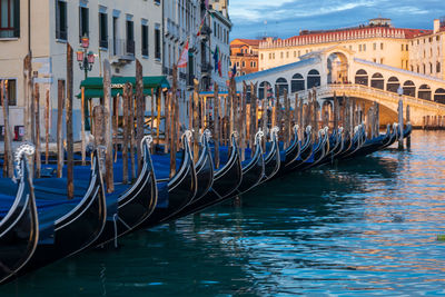 Boats moored in canal with city in background