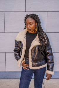 Young woman standing against wall