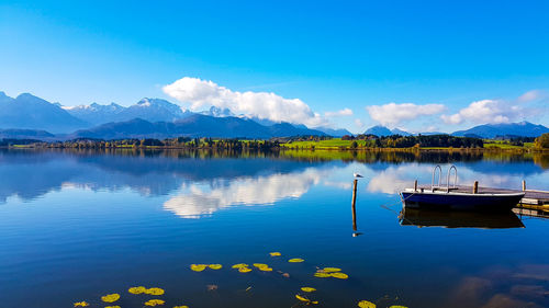 Boats in calm lake against blue sky