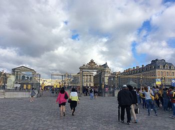 Tourists at amusement park against cloudy sky