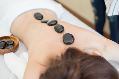 High angle view of topless woman with stones on back in spa