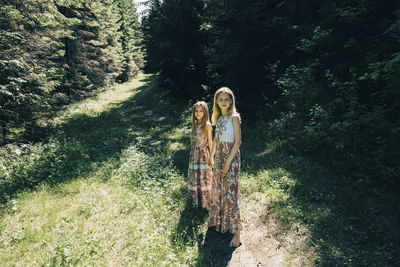 Portrait of sisters holding hands while standing in forest