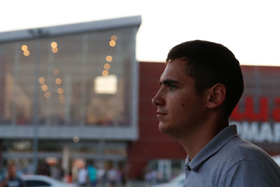 Man face profile. 20s man standing near shopping mall. night summer. portrait of young man.