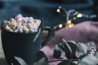 Close-up of marshmallows in mug by plant on table
