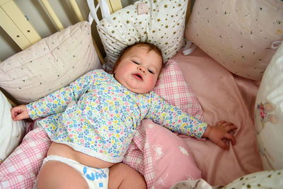 Cute girl of ten months old, playing alone in a crib at home in the afternoon or in the morning.