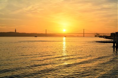 View of suspension bridge over sea during sunset