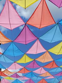 Low angle view of multi colored umbrellas hanging against blue sky