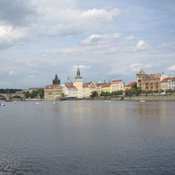 Buildings at waterfront against cloudy sky