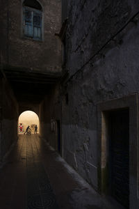 Rear view of people walking on narrow street amidst buildings