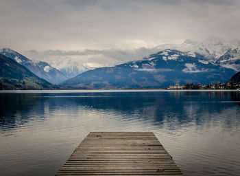 Pier over lake by mountains against sky