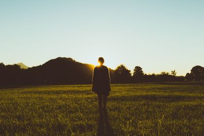 Silhouette woman standing on field against clear sky during sunset