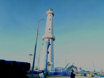 Low angle view of cranes at harbor against clear blue sky