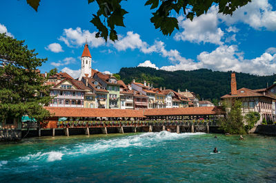 Buildings by sea against sky