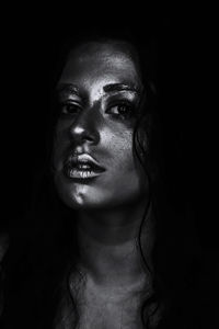 Close-up portrait of young woman against black background