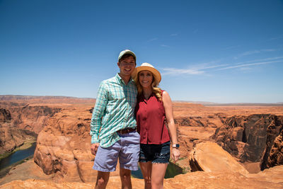 Portrait of couple standing on rock against sky