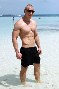 Portrait of shirtless man standing at beach