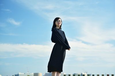 Young woman looking away against sky