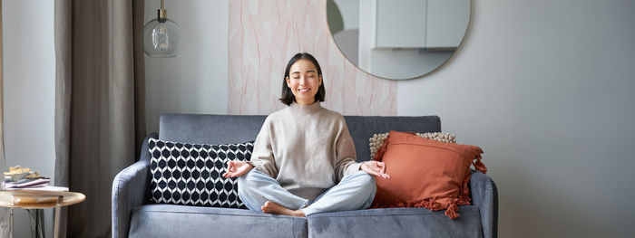 Portrait of young woman sitting on sofa at home