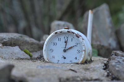 Close-up of old clock on rock