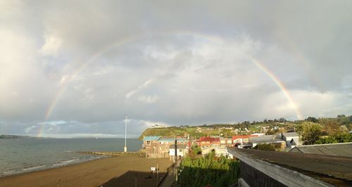 Rainbow over city against cloudy sky