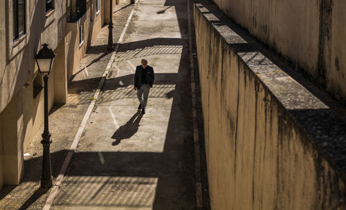 Man in black suit walking on path with sunlight and shadow