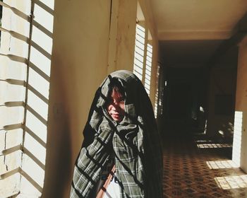 Portrait of girl wrapped in textile while standing in corridor