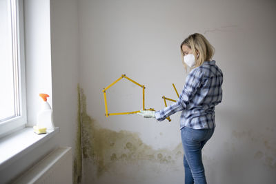 Side view of woman standing against wall