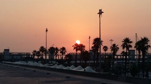 Illuminated street lights against sky during sunset