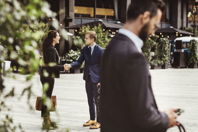 Male and female entrepreneurs shaking hands while standing outdoors